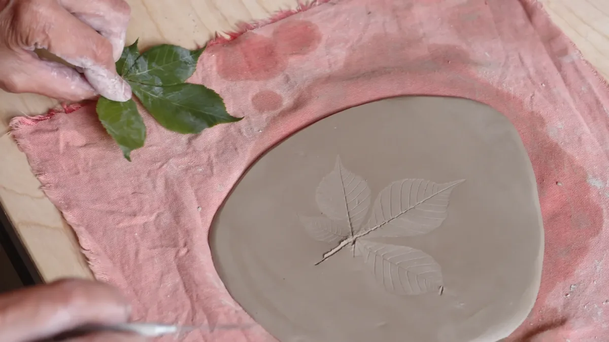 Three fine leaf impressions visible in the surface of a broad clay slab.