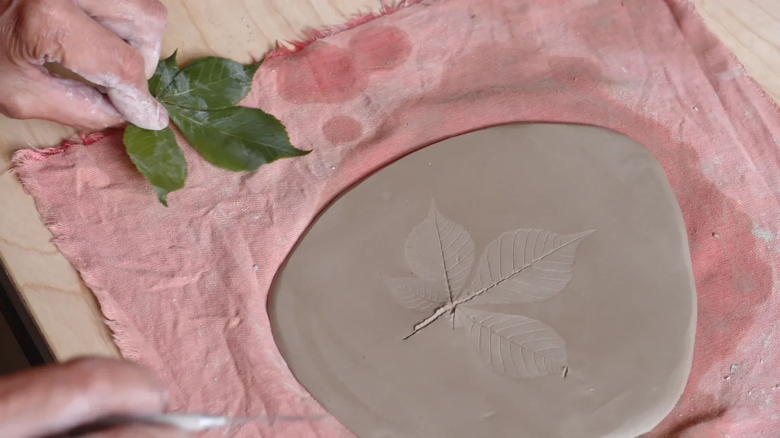 Three fine leaf impressions visible in the surface of a broad clay slab.
