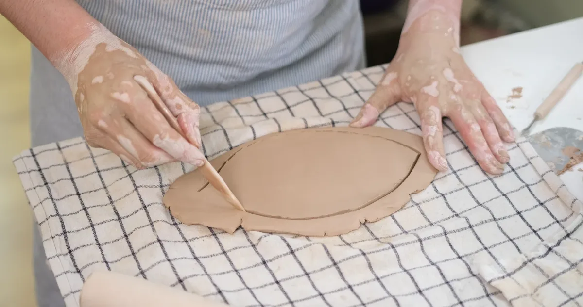 A modelling tool following the outline of a broad leaf in a clay slab.
