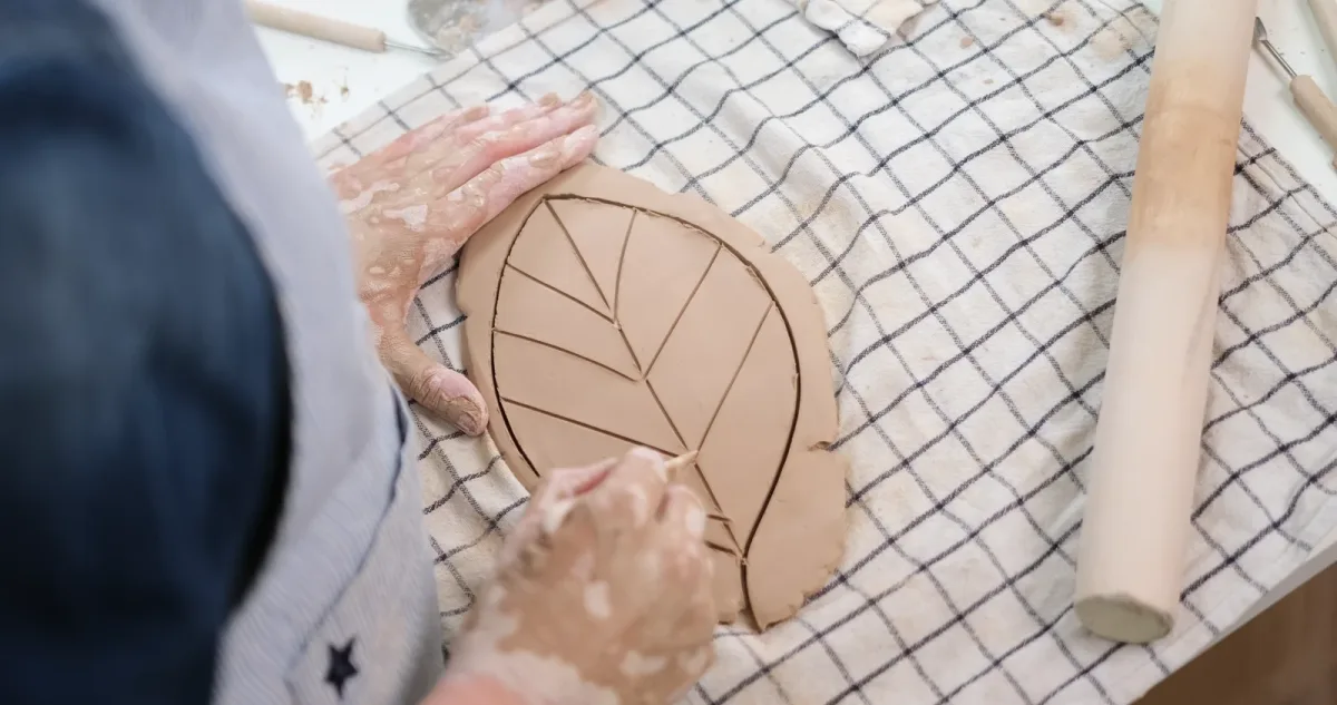 A modelling tool making diagonal veins in a supported clay leaf.