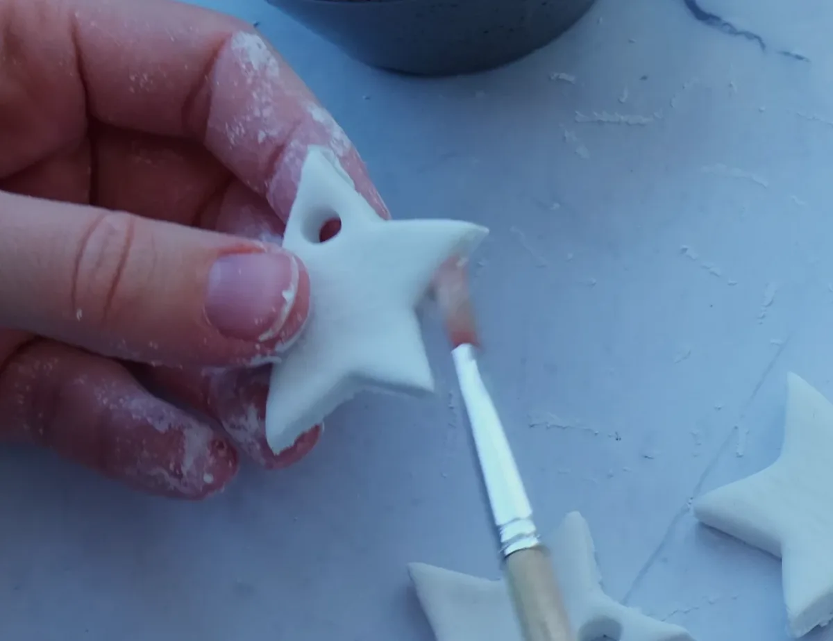 Close view of a clay star with an open hanging hole below its upper tip.